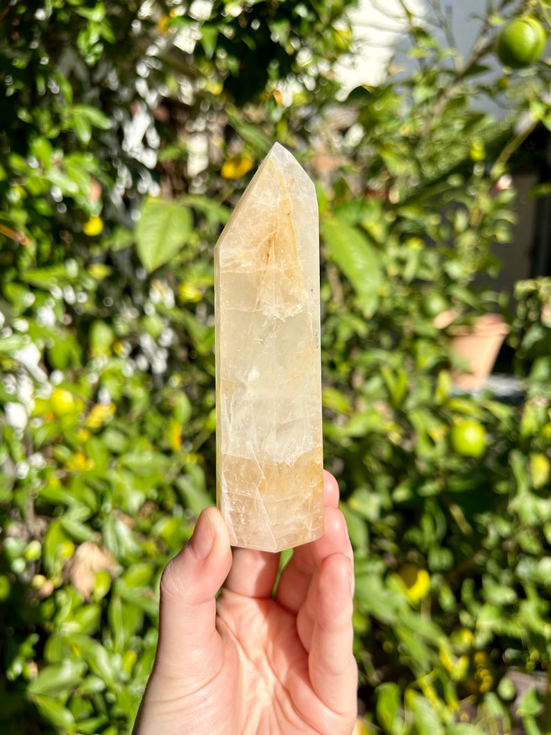 Puede incluir: Una punta de cristal transparente de color amarillo claro con una punta puntiaguda. El cristal es liso y pulido, con una apariencia transl&uacute;cida.
