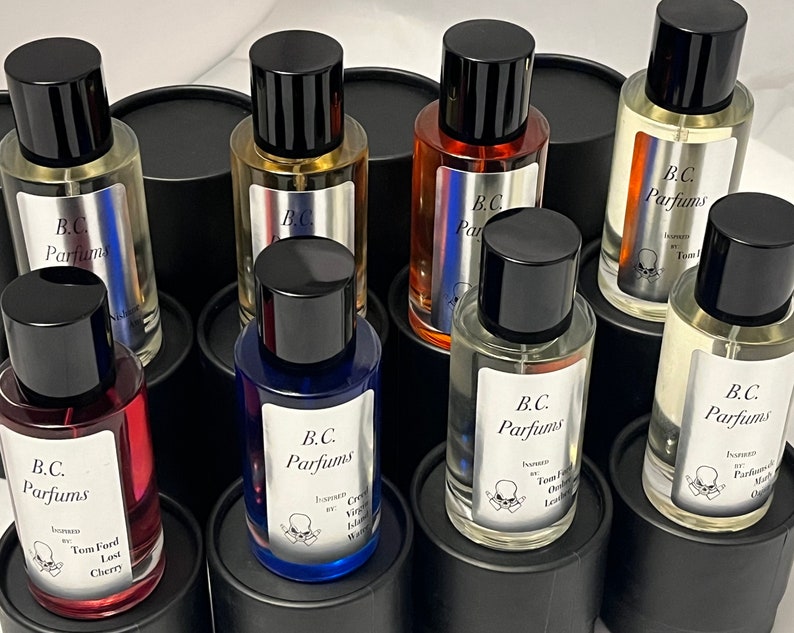 May include: A collection of eight glass bottles of perfume with black lids and labels. The labels feature the text "B.C. Parfums" and the names of different fragrances, including "Tom Ford Last Cherry", "Creed Virgin Island Water", and "Tom Ford Oud Leather".