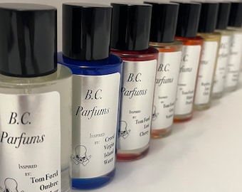 May include: A row of eight small glass bottles with black caps. Each bottle has a silver label with the text "B.C. Parfums" and a skull graphic. The labels also include the text "Inspired by:" followed by the name of a fragrance. The bottles are arranged in a line from left to right, with the bottles on the left side of the image being closer to the viewer.