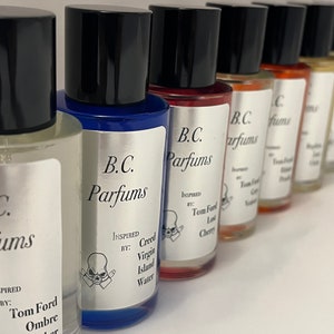 May include: A row of eight small glass bottles with black caps. Each bottle has a silver label with the text "B.C. Parfums" and a skull graphic. The labels also include the text "Inspired by:" followed by the name of a fragrance. The bottles are arranged in a line on a white surface.