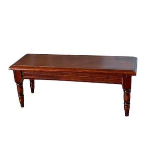 May include: A rectangular wooden bench with a smooth, dark brown stained finish. The bench features a flat top surface with beveled edges and four turned legs that taper toward the bottom, providing a stable base for this furniture piece.