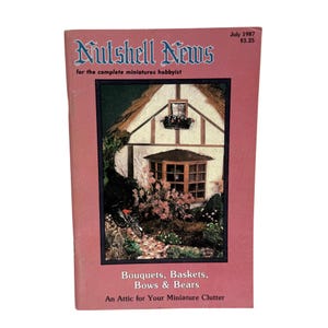 May include: A vintage copy of "Nutshell News" magazine, July 1987 issue. The cover features a miniature cottage scene with a thatched roof and pink flowers. Text includes "Bouquets, Baskets, Bows & Bears" and "An Attic for Your Miniature Clutter."