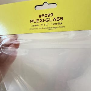May include: Two clear plexi-glass sheets in a yellow cardboard header card. The text reads #5099 PLEXI-GLASS, 2 sheets, 9 inches by 12 inches, 1 mm thick, Houseworks 2010 All rights reserved. Made in Thailand. The sheets are transparent and flexible.