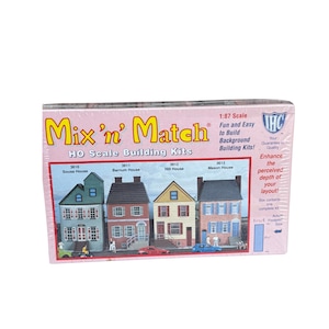 May include: A pink box of Mix 'n' Match HO scale building kits. The box features images of four different model houses: Sousa House, Barnum House, Hill House, and Mason House. The box also includes text that says "Fun and Easy to Build Background Building Kits!"