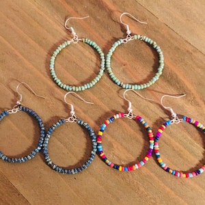 May include: Four pairs of beaded hoop earrings. Two pairs are turquoise blue, one pair is dark blue, and one pair is multi-colored.