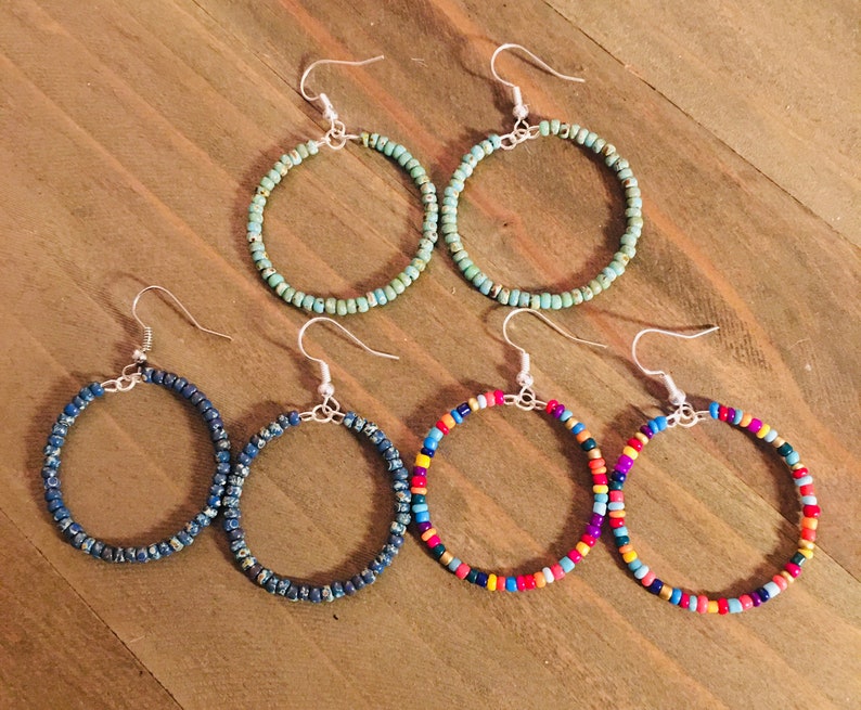 May include: Four pairs of beaded hoop earrings. Two pairs are turquoise blue, one pair is dark blue, and one pair is multi-colored.