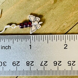 May include: Silver butterfly dangle earrings with purple beads. The earrings measure approximately 1 inch in length.