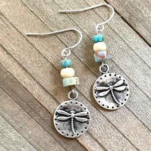 May include: A pair of silver dangle earrings with a dragonfly charm and turquoise and white beads.