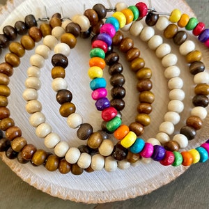 May include: Four pairs of wooden hoop earrings. One pair is made of natural wood beads, one pair is made of brown wood beads, one pair is made of white wood beads, and one pair is made of colorful wood beads.