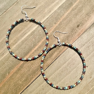 May include: A pair of large hoop earrings made with colorful, speckled beads. The earrings are silver and have a simple hook closure.