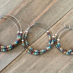 May include: Three pairs of hoop earrings with a double row of colorful beads. The beads are a mix of brown, blue, green, and red.