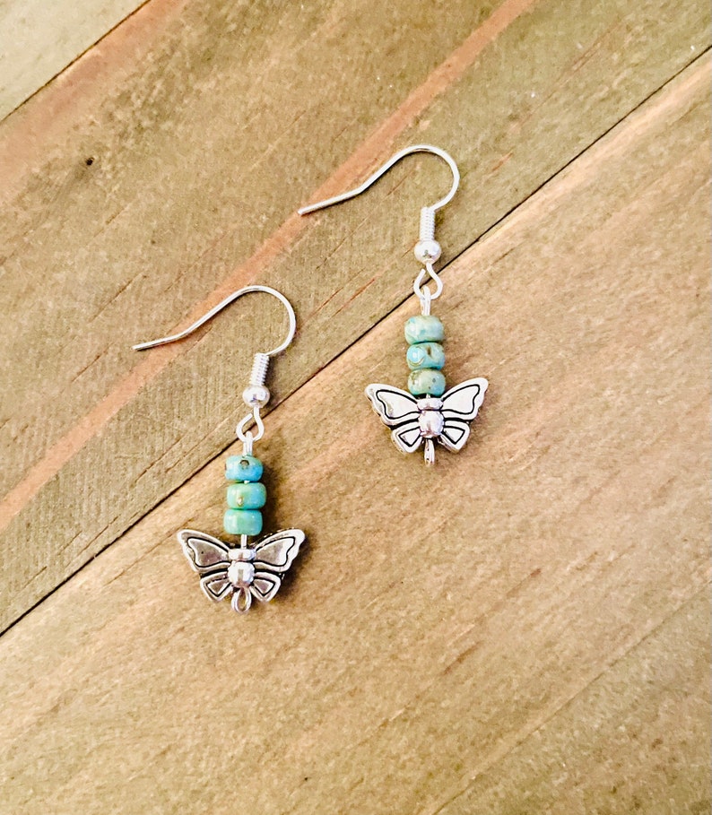 May include: A pair of silver butterfly earrings with turquoise blue beads.