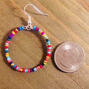 May include: Colorful beaded hoop earrings with a silver hook closure. The earrings are about the size of a US quarter.