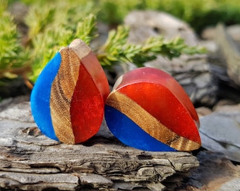 May include: Two teardrop-shaped resin earrings with wood inlay. One earring is red and blue, the other is blue and red.