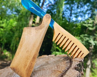 May include: A folding comb featuring a light-colored wooden handle and a matching wooden comb section, connected by a hinge. The spine of the comb is crafted from a translucent, vibrant blue resin material that extends into the handle and teeth area.