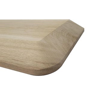 May include: A close-up of the edge of a light brown wooden countertop with a rounded edge.