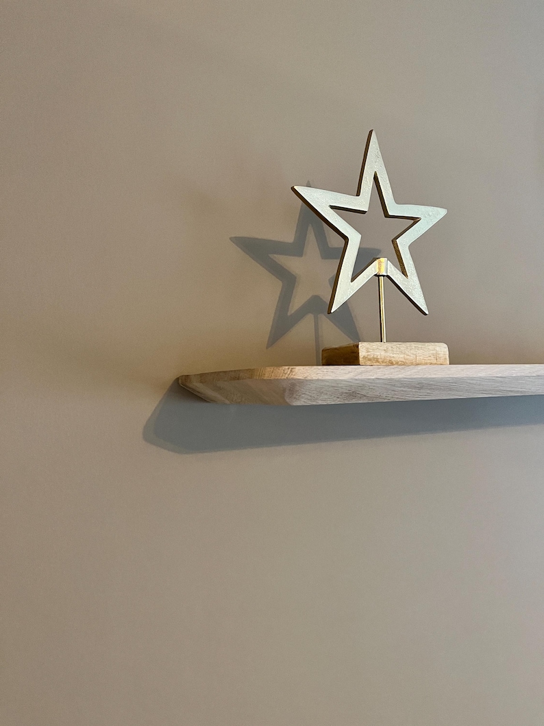 May include: A gold star-shaped ornament on a wooden shelf