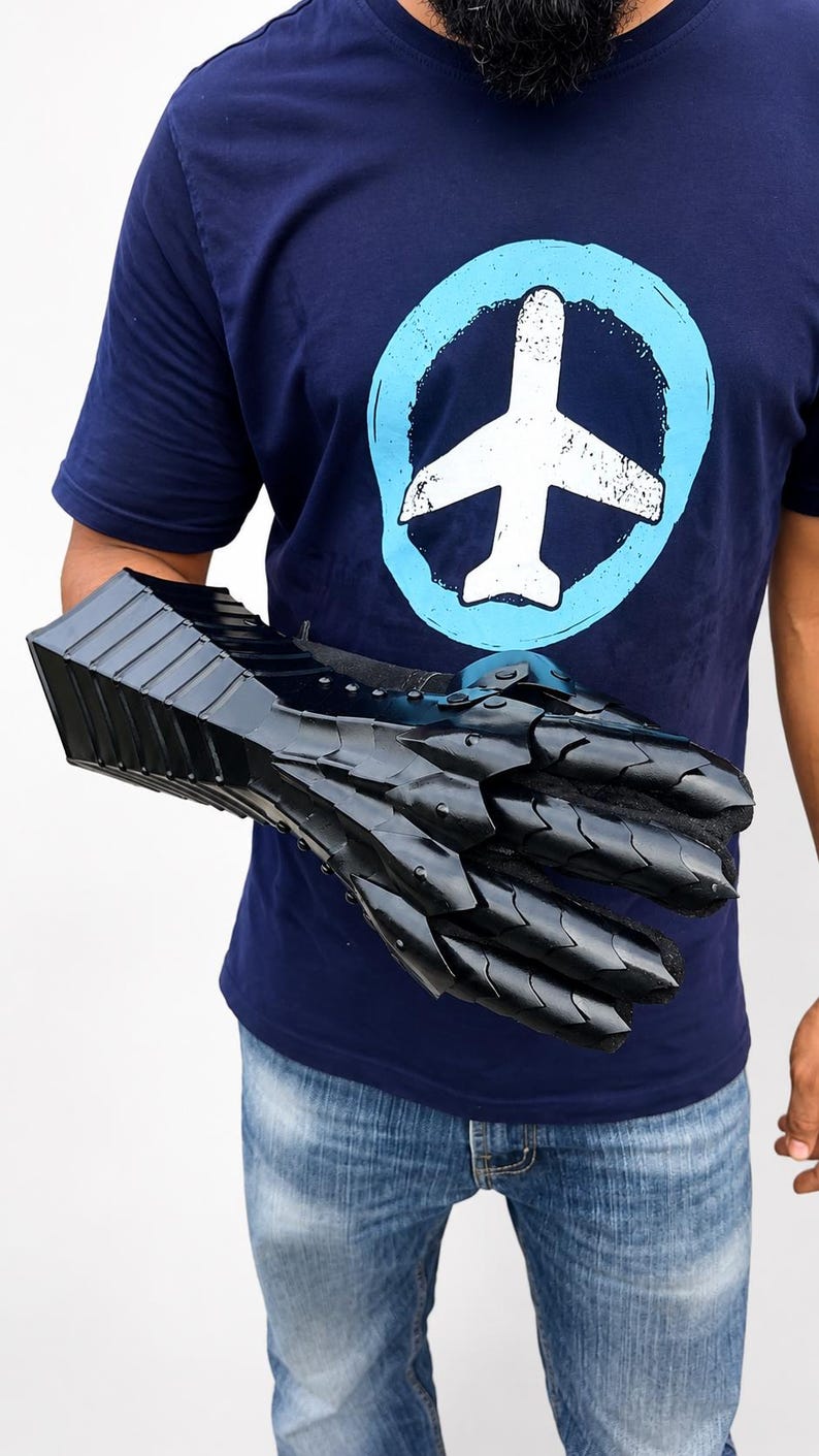 K&ouml;nnte beinhalten: Ein schwarzer, beweglicher Metallhandschuh mit &uuml;berlappenden Platten, die Hand und Unterarm bedecken. Der Handschuh hat eine gl&auml;nzende Oberfl&auml;che und ist aus mehreren Segmenten gefertigt, die Beweglichkeit erm&ouml;glichen, mit einem detaillierten Design.