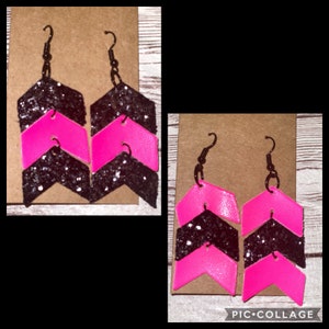 May include: A pair of pink and black chevron earrings with glitter accents. The earrings are made of leather and have a simple hook closure.