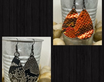 May include: Two pairs of dangle earrings with a teardrop shape. The earrings are made of leather with a snake skin pattern. One pair is black and gray, the other is orange and brown.