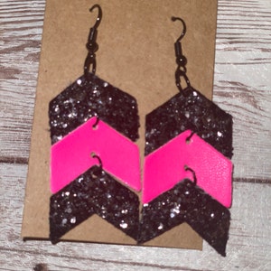 May include: A pair of black and pink glitter chevron earrings with silver hooks.