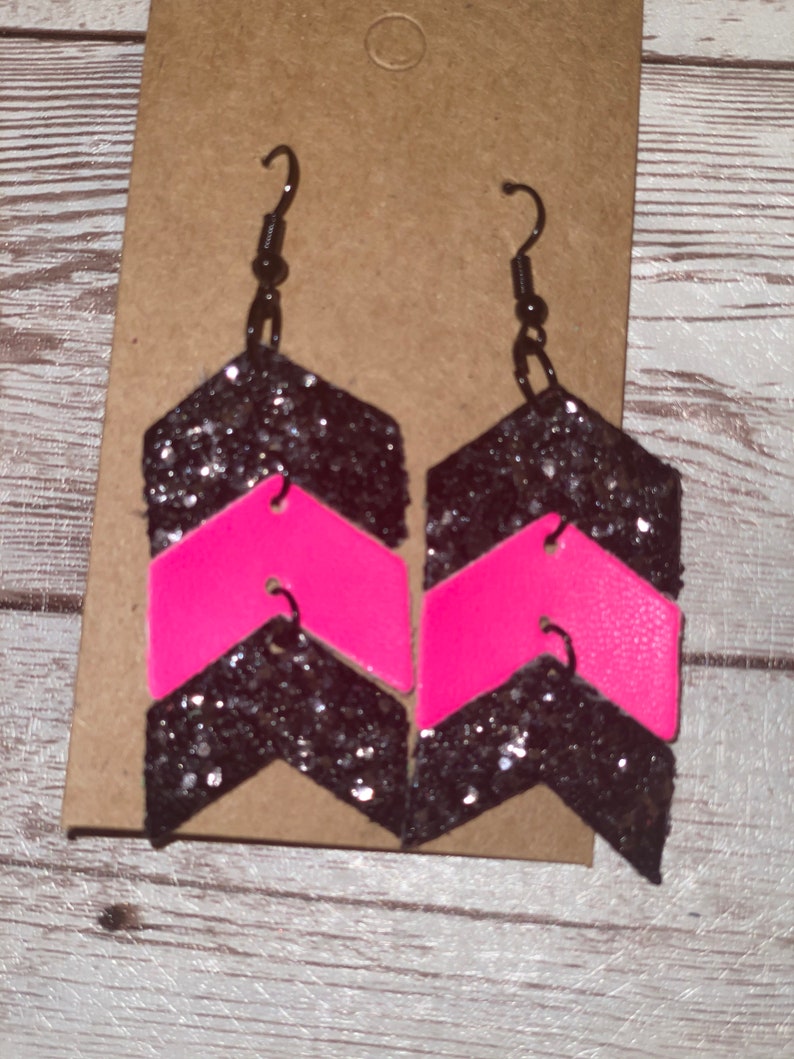 May include: A pair of black and pink glitter chevron earrings with silver hooks.