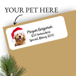 May include: A white label with a golden retriever wearing a red Santa hat. The label has the text "Megan Benjamin, 1234 Somewhere, Special, Illinois 12345" printed on it.