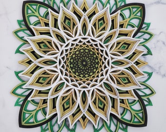 Puede incluir: Un diseño de mandala multidimensional y en capas con acentos verdes, blancos y dorados. El mandala está hecho de madera y tiene un patrón geométrico intrincado.