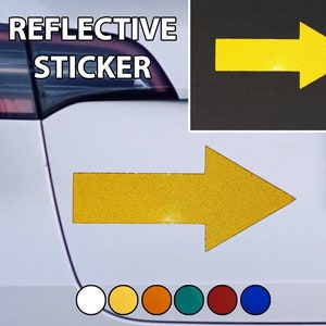 Może przedstawiać: Naklejka z żółtą, odblaskową strzałką z napisem "REFLECTIVE STICKER" na białym samochodzie. Naklejka jest przeznaczona do umieszczenia na tylnej części pojazdu, aby ostrzec innych kierowców.