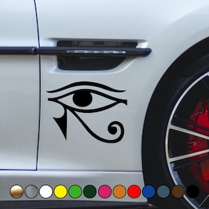 May include: A black and white vinyl sticker of the Eye of Horus, an ancient Egyptian symbol, on a white car door.