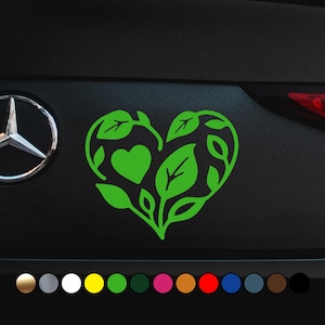 Può includere: Un adesivo verde a forma di cuore con un design a foglie. Il cuore è riempito di foglie e un cuore più piccolo al centro. Sotto sono mostrate diverse opzioni di colore.