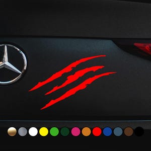Könnte beinhalten: Roter Krallenabdruck-Aufkleber für ein Auto. Der Aufkleber ist auf einem schwarzen Auto zu sehen. Der Aufkleber ist in verschiedenen Farben erhältlich.