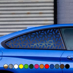 Può includere: Un'auto blu con una pellicola per finestrini a motivo geometrico. La pellicola è di colore blu scuro e presenta un motivo ripetitivo di triangoli. L'auto è parcheggiata davanti a un muro di mattoni.