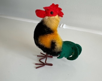 May include: A vintage plush toy rooster with a red comb and wattle, black, yellow, and green feathers, and wire legs.