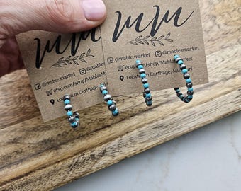 May include: Two pairs of turquoise and silver hoop earrings. The earrings are on a brown card with the text "mam" and social media handles for @mable.market and @mablesmarket.