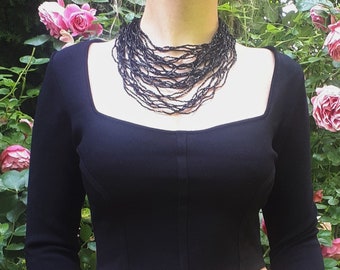 Vintage 90's black beaded 30 multi strand wavy / lacy goth glass necklace that closes with a clasp