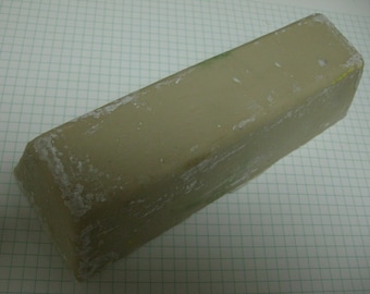 Pode incluir: Um bloco retangular de composto de polimento cinza com um revestimento branco em pó.