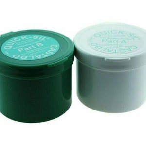 May include: Two containers of two-part RTV silicone rubber sealant. The green container is labeled "Quick-Sil Part B" and the white container is labeled "Quick-Sil Part A".