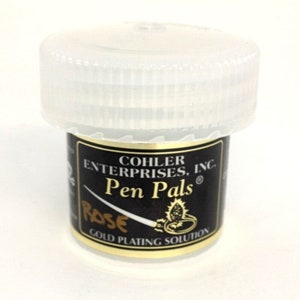 May include: A small, clear plastic jar with a black label that reads "Cohler Enterprises, Inc. Pen Pals Rose Gold Plating Solution".