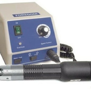 May include: A Foredom electric handpiece with a speed control knob and a foot pedal. The handpiece is connected to a power unit with a cord and a foot pedal.