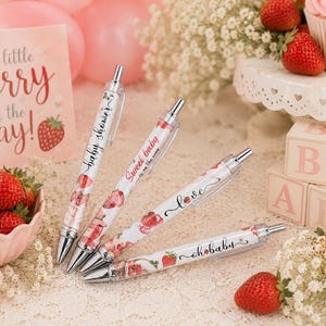 May include: Four retractable ballpoint pens featuring a white barrel with a strawberry pattern and text. The pens display the phrases "baby shower," "sweet baby," "love," and "oh baby" in black script, accented with silver metal clips and tips.