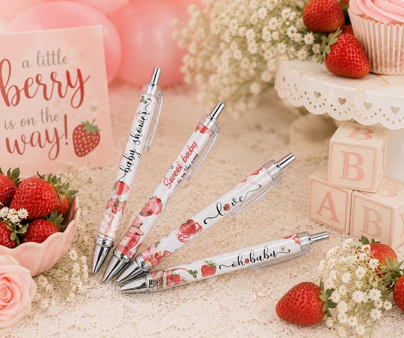 May include: Four retractable ballpoint pens featuring a white barrel with a strawberry pattern and text. The pens display the phrases "baby shower," "sweet baby," "love," and "oh baby" in black script, accented with silver metal clips and tips.