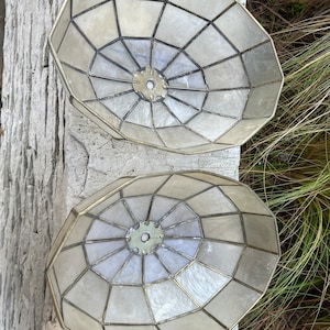 May include: Two white, round, lampshades with a geometric pattern of squares and a brass frame.