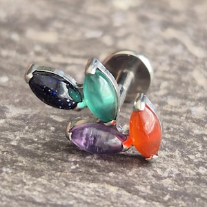 May include: A silver-toned labret stud featuring four marquise-cut gemstones in blue, green, purple, and orange. The gemstones are set in a cluster design, creating a unique and eye-catching piece of jewelry.