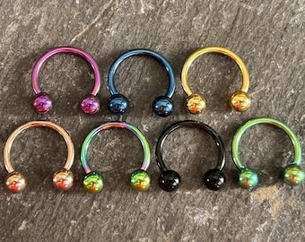 Puede incluir: Ocho joyas corporales circulares en forma de herradura de diferentes colores con extremos de bola. Los colores son rosa, azul, oro, oro rosa, verde, negro y dos tonos de verde.