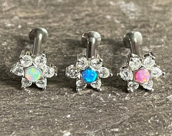 May include: Three silver flower-shaped body jewellery pieces with opal stones in white, blue, and pink.