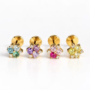May include: Four gold-tone flat back stud earrings, each featuring a cluster of four round-cut coloured gemstones arranged in a flower shape, accented with tiny clear stones. The stones include blue, green, purple, pink, red, and yellow hues.