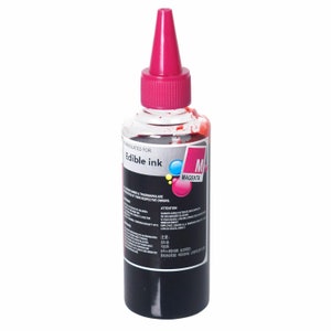 May include: A clear plastic bottle of edible magenta ink with a pink cap. The bottle is labeled "Edible Ink" and "M Magenta".