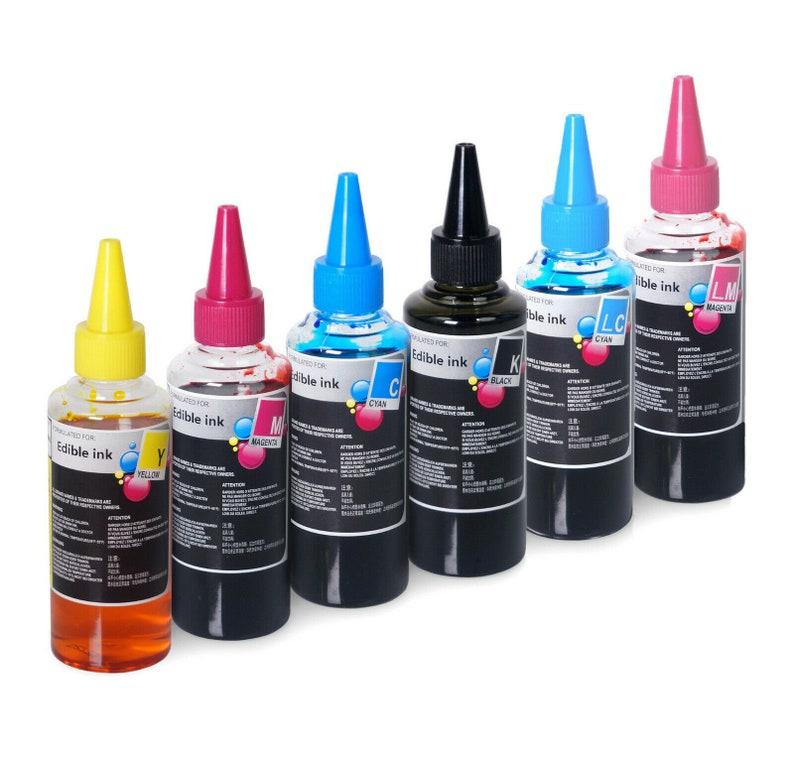 May include: Six bottles of edible ink in different colors: yellow, magenta, cyan, black, light cyan, and magenta. Each bottle has a label that says "Edible Ink" and the color of the ink.