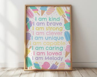 May include: A framed print with a light wood frame. The print features colorful ice cream illustrations around the border. The text reads "I am kind, I am brave, I am strong, I am clever, I am unique, I am capable, I am caring, I am loved, I am Melody."